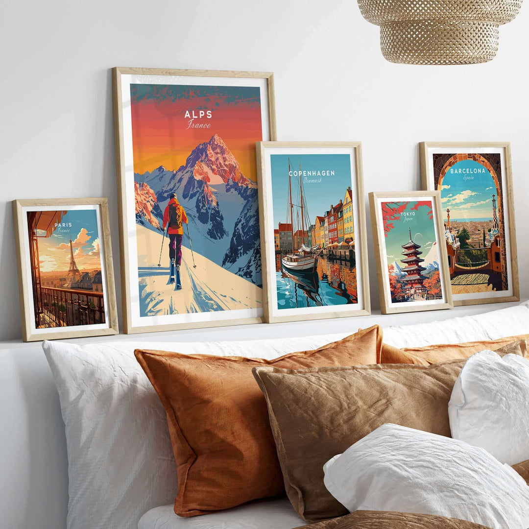 Alps Print France ski poster in a frame, showcasing vibrant colors and snowy peaks, displayed with other travel posters above a sofa.