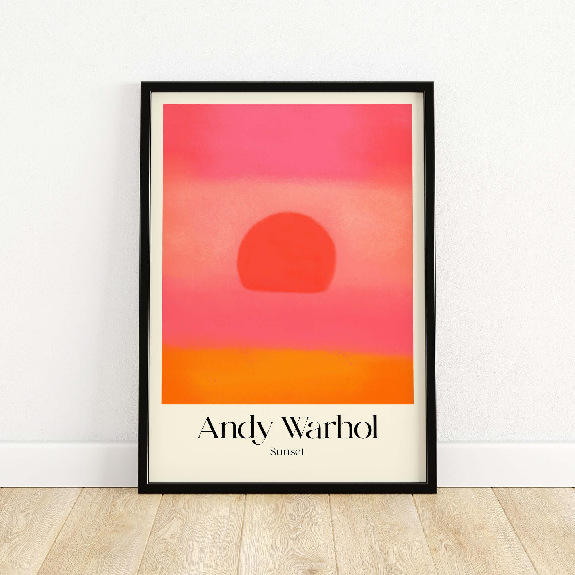 Andy Warhol Sunset Pink Orange Pop Art Print Modern Abstract Poster Wall Art displayed in a black frame on a wooden floor.