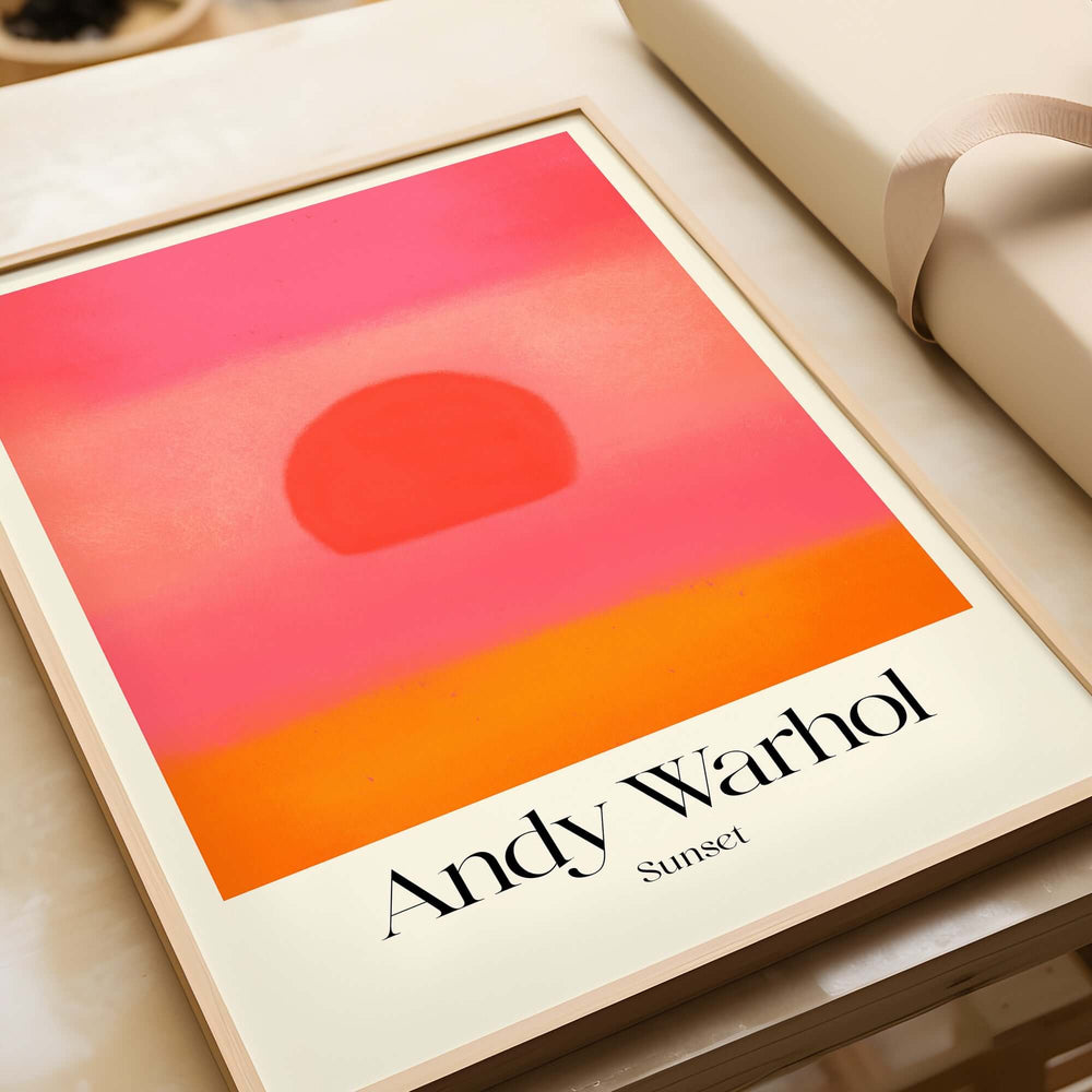 Andy Warhol Sunset Pink Orange Pop Art Print Modern Abstract Poster Wall Art displayed on a table with a gift.