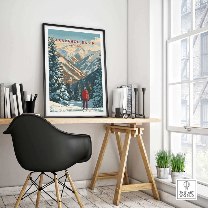 Arapahoe Basin wall art featuring snowy mountainous landscape, displayed on a wall above a wooden desk in a modern room.