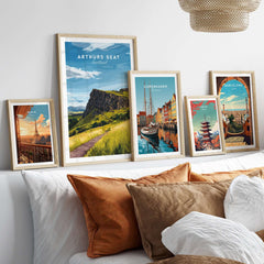 Arthurs Seat Scotland Travel Print displayed among other travel prints on a cozy sofa.