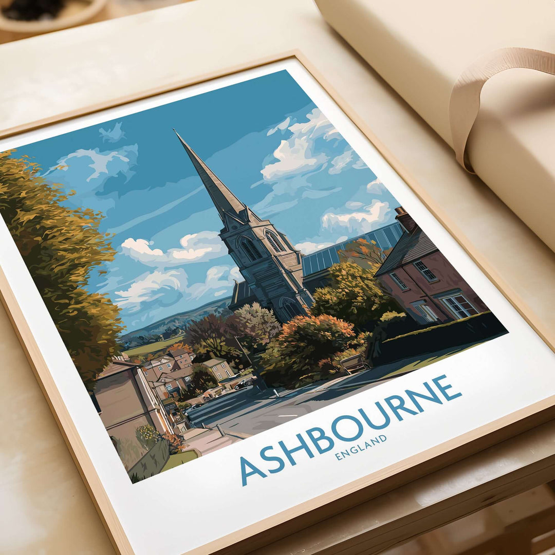 Ashbourne travel poster showcasing a UK village scene with a church and scenic countryside, framed and displayed.
