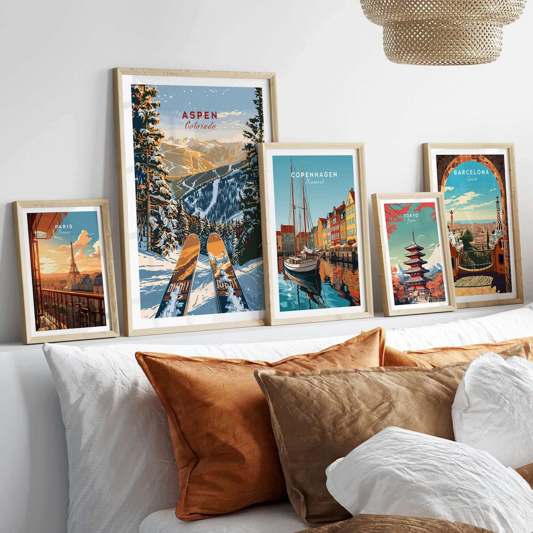 Aspen Print Colorado ski poster displayed with other travel posters in modern frames above a cozy bed with decorative pillows.