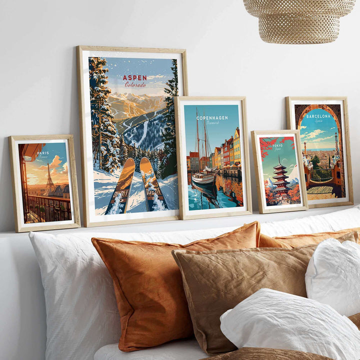 Aspen Print Colorado ski poster displayed with other travel posters in modern frames above a cozy bed with decorative pillows.