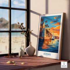 Aswan Travel Poster displayed indoors beside a vase and coastal scenery, capturing the beauty of Aswan in vibrant colors.