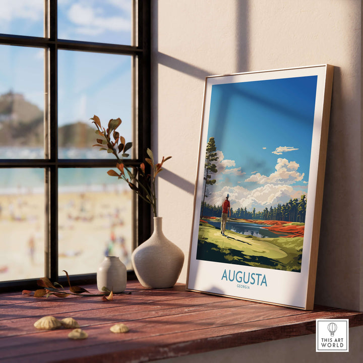 Augusta National Print artwork displayed on a wooden table by a window, featuring a golfer amid scenic Georgia landscape.