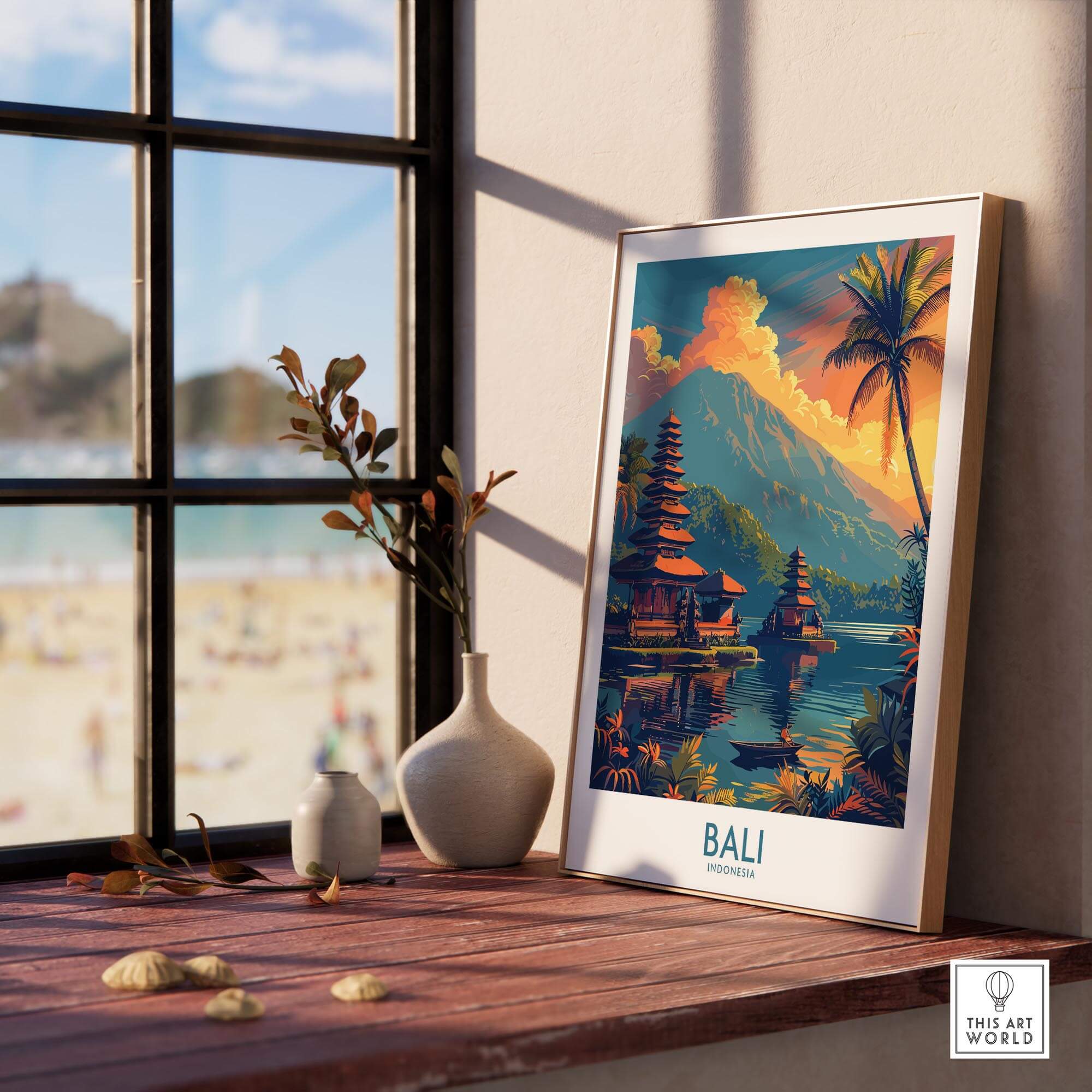 Bali Sunset Wall Art Print displayed on a wooden table next to a window, showcasing a serene beach view.