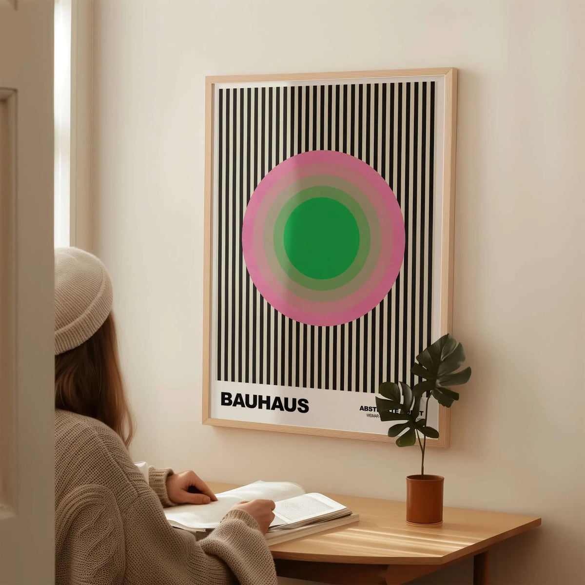Bauhaus Exhibition Prints - Concentric Circles Poster Pink Green Striped Art displayed on a wall with a person reading.