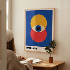 Bauhaus Exhibition Prints - Abstract Eye Circles Poster - Blue Yellow Red Primary Art displayed on wall with a person reading.