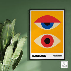 Bauhaus Exhibition Prints - Abstract Eyes Poster Geometric Orange Red Blue Art on a green wall with plants.