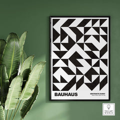 Bauhaus Exhibition Prints - Geometric Triangle Pattern Poster Black White Abstract hanging on a green wall with plants.
