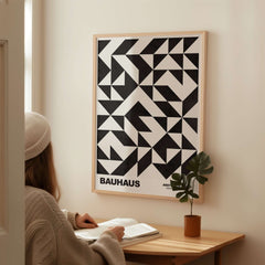 Bauhaus Exhibition Prints - Geometric Triangle Pattern Poster Black White Abstract displayed on wall near a woman reading at a desk.