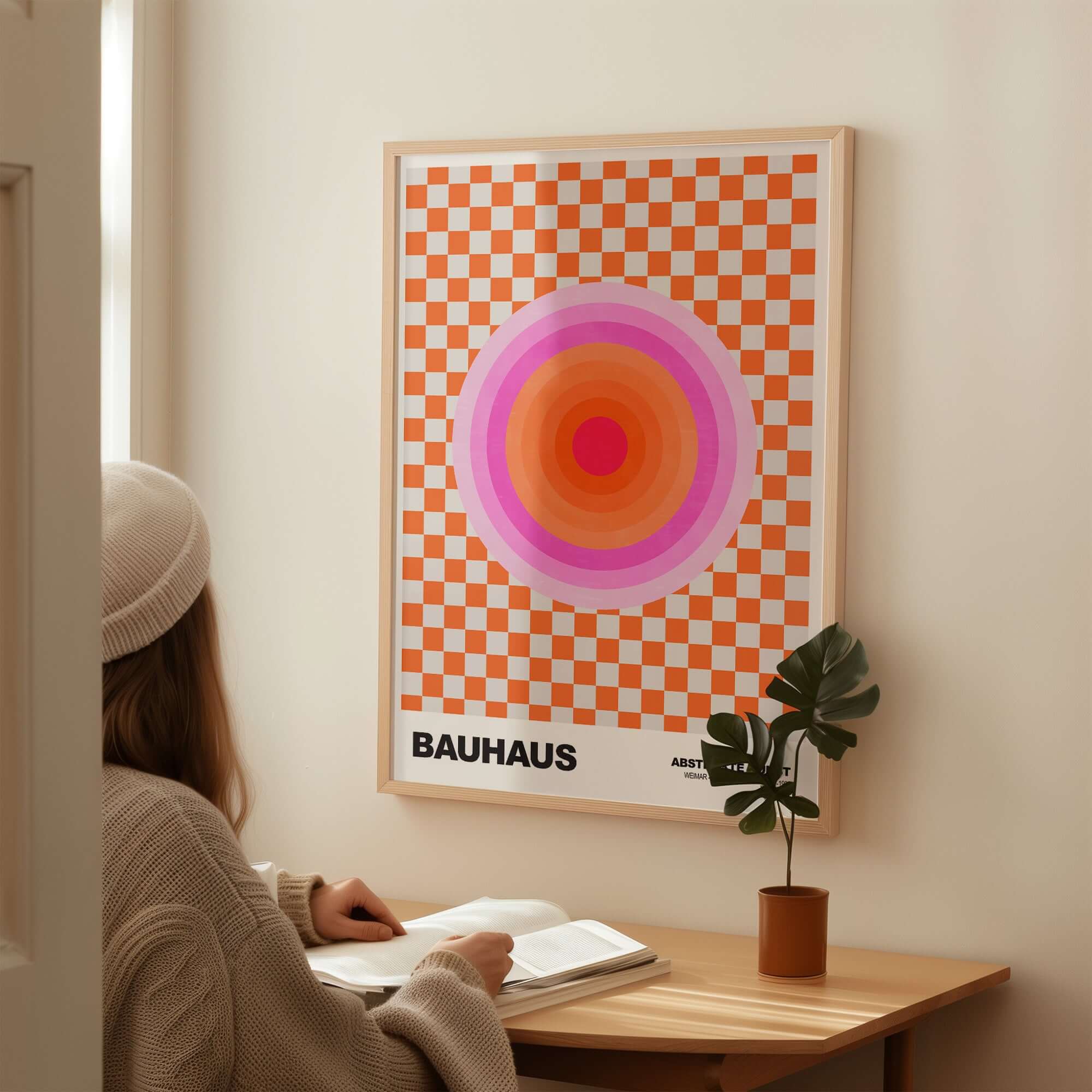 Bauhaus Exhibition Prints - Pink Circles Poster Orange Checkerboard Art in a cozy living space with a person reading.