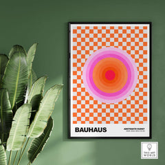 Bauhaus Exhibition Prints - Pink Circles Poster Orange Checkerboard Art on a green wall with plants.