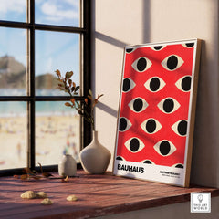Bauhaus Exhibition Prints - Repeating Eyes Pattern Poster Red Black Cream Art displayed beside a window with scenic view.