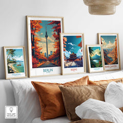 Framed travel posters of Berlin, Beijing, Grand Canyon, Philippines, and Costa Rica on a sofa wall.