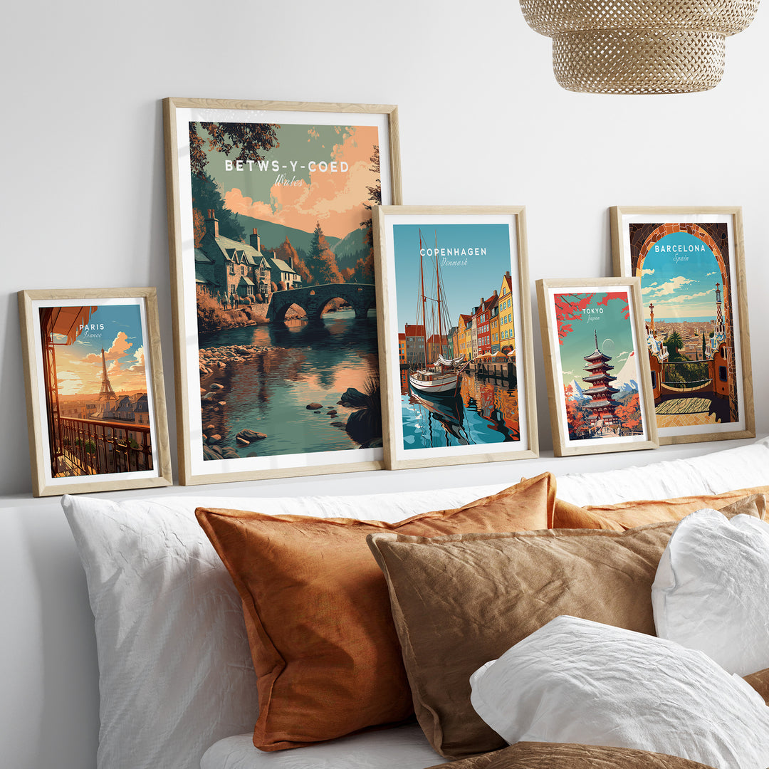 Betws-y-Coed Wales village art print displayed among other scenic travel posters on a cozy couch.