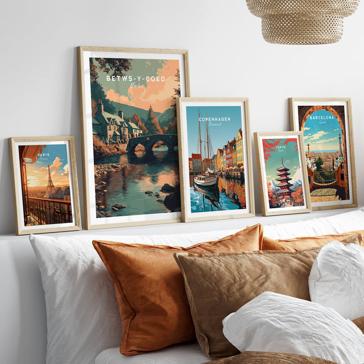 Betws-y-Coed Wales village art print displayed among other scenic travel posters on a cozy couch.