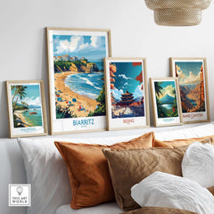 Biarritz Travel Poster displayed among other travel art prints on a cozy couch, showcasing coastal beauty.