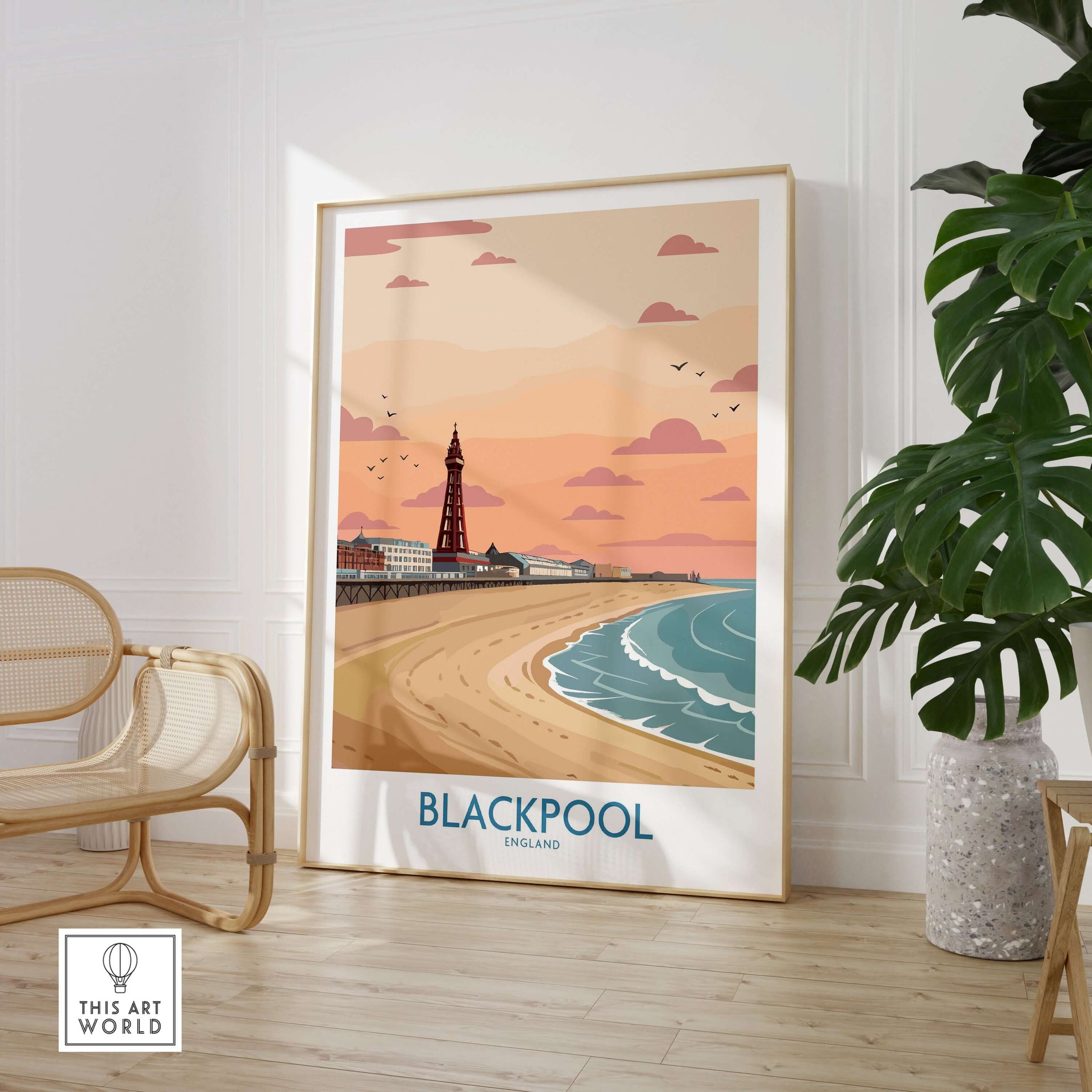 Blackpool Sunset Tower Beach Art Print | Pink Sky UK Coastal Poster displayed in a cozy interior with plants.