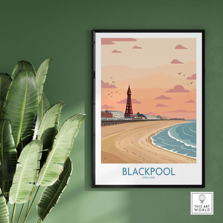 Blackpool Sunset Tower Beach Art Print | Pink Sky UK Coastal Poster displayed on wall with tropical leaves.