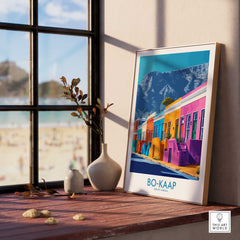Bo-Kaap Print showcasing vibrant colors and traditional designs, set on a windowsill with a beach view in Cape Town.