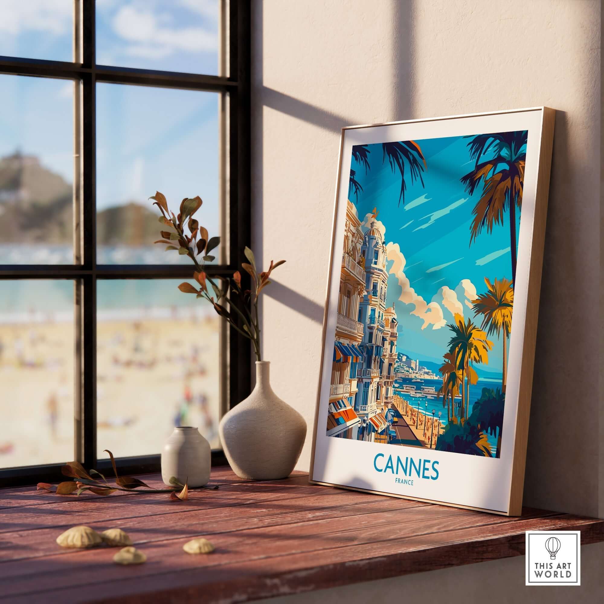 Cannes Art Print framed on a windowsill showcasing a vibrant cityscape of Cannes, France with palm trees.