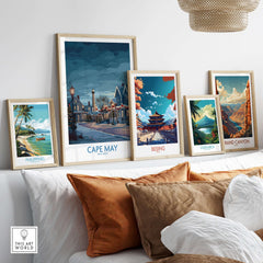 Cape May Christmas Lights Poster - Snowy Seaside Decor displayed among framed travel posters on a cozy sofa.