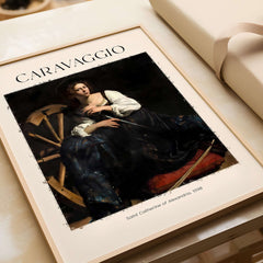 Caravaggio Art Print - Saint Catherine of Alexandria 1598 in a stylish frame on a wooden surface.