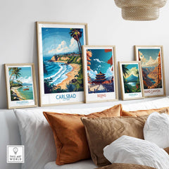 Carlsbad Poster California displayed among other travel posters on a cozy couch, showcasing vibrant coastal art.