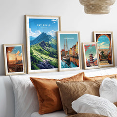 Cat Bells Wall Art Poster - Lake District displayed among other travel posters on a stylish bed with decorative cushions.