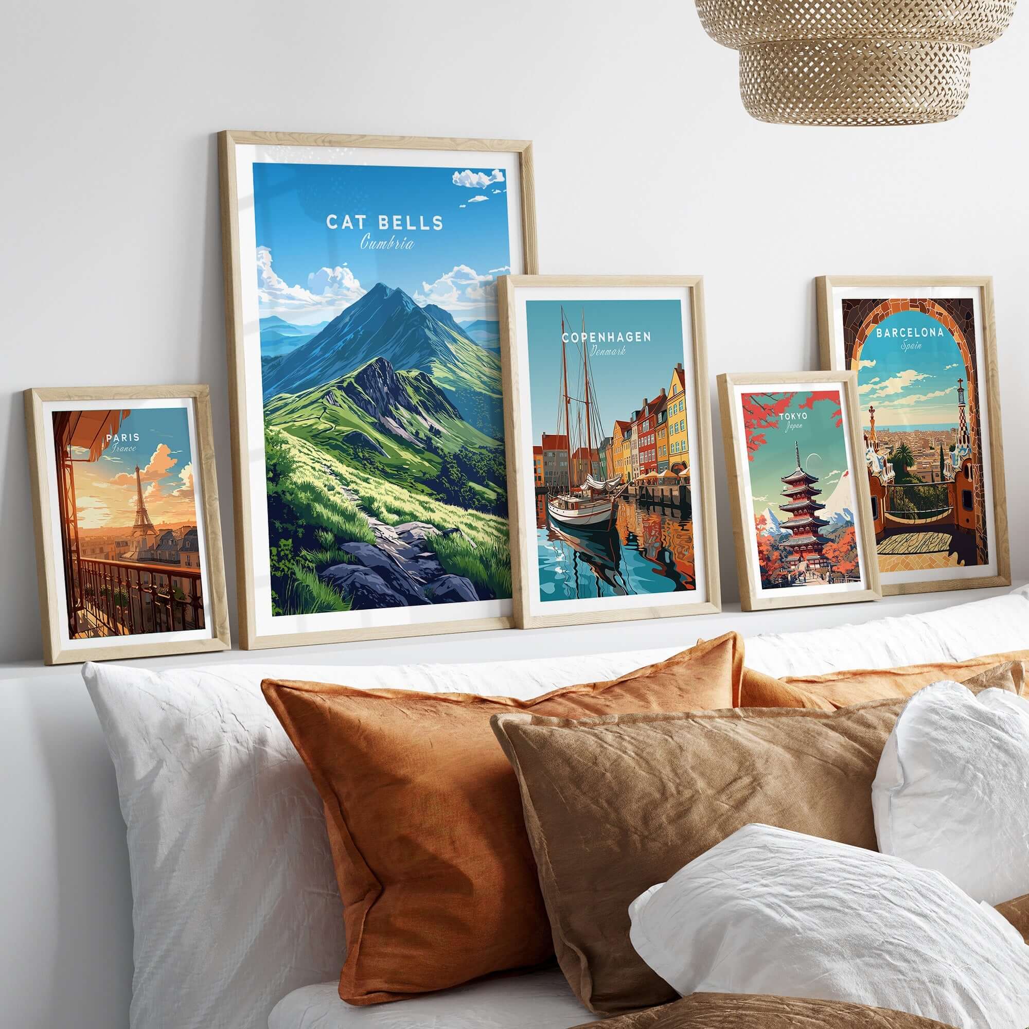 Cat Bells Wall Art Poster - Lake District displayed among other travel posters on a stylish bed with decorative cushions.