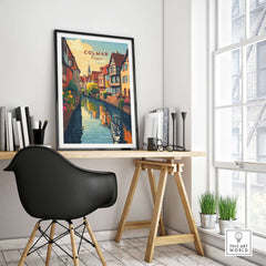 Colmar Travel Print displayed in a modern home office setting, featuring vibrant illustrations and a scenic canal view.