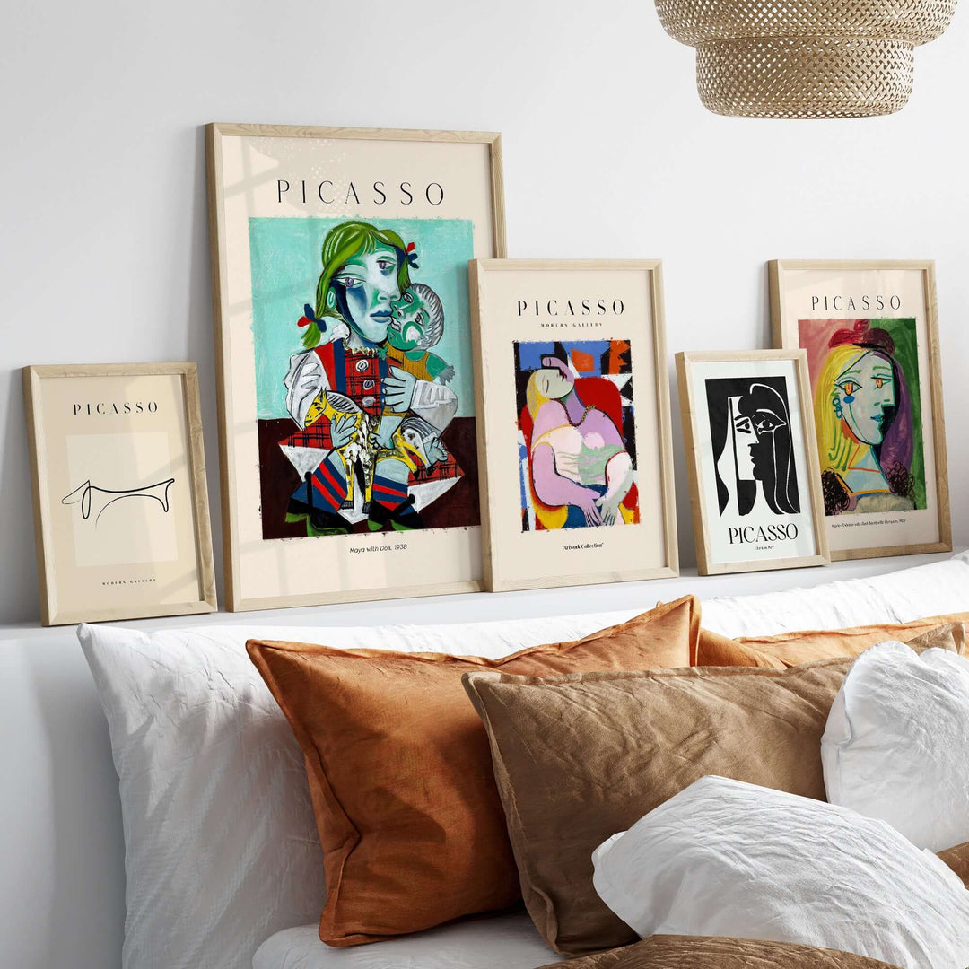 Colorful collection of framed Picasso prints featuring Cubist art arranged on a modern shelf with decorative cushions.