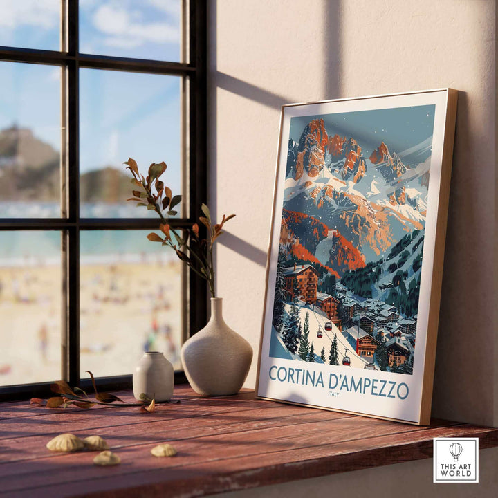 Framed Cortina d'Ampezzo print displayed on a windowsill, capturing a scenic view of the Italian Alps, in a bright and cozy setting.