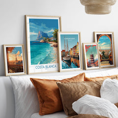 Costa Blanca Poster - Spain Wall Art displayed among other city posters on a stylish couch with decorative pillows.