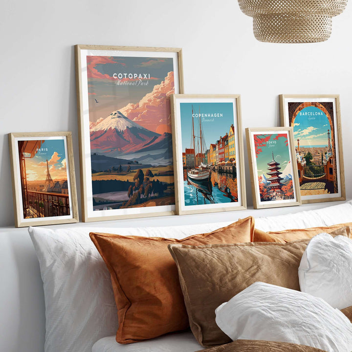 Framed travel posters of Cotopaxi, Copenhagen, and Barcelona above a stylish sofa with decorative pillows.
