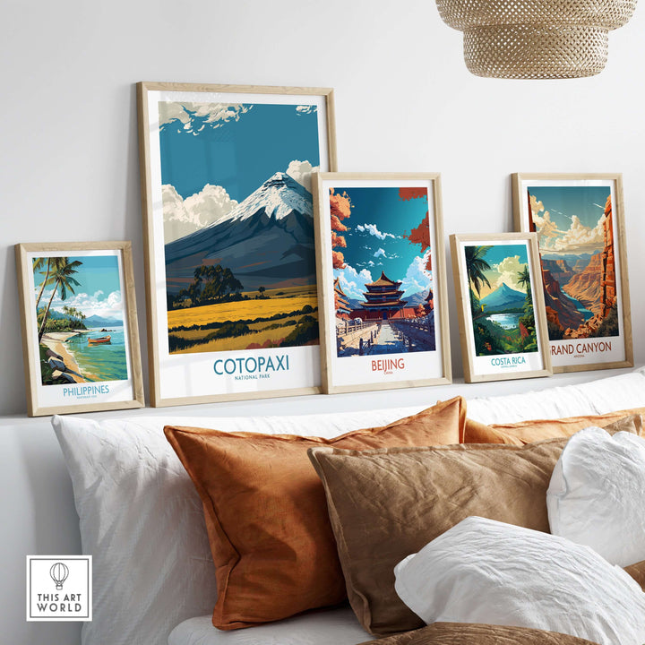 Collection of travel posters including Cotopaxi volcano in Ecuador, displayed on a couch with decorative pillows.