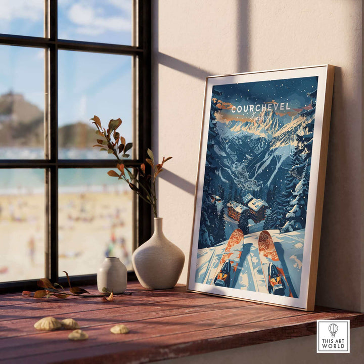 Framed Courchevel print on windowsill, featuring scenic winter landscape of France's ski resort, with blue sky and snowy mountains.