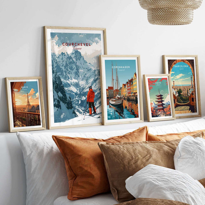 Collection of framed travel posters including a Courchevel ski scene, displayed on a stylish bed with cozy pillows.