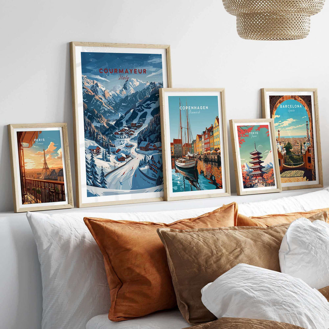 A stylish room featuring framed travel posters of Courmayeur, Copenhagen, and Barcelona above a cozy bed with decorative cushions.