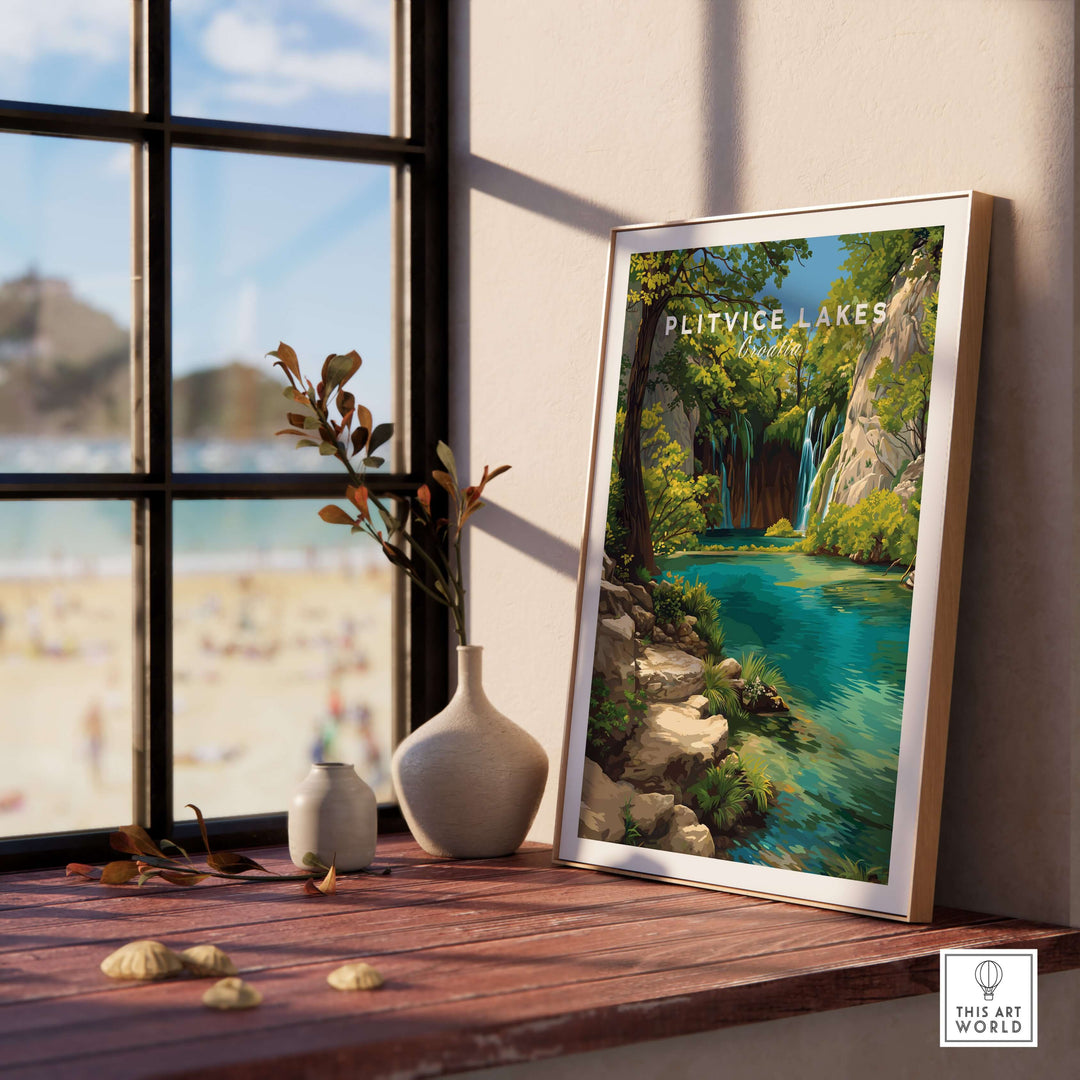 Framed Plitvice Lakes waterfall poster on a wooden table by a window, showcasing serene nature landscape decor.