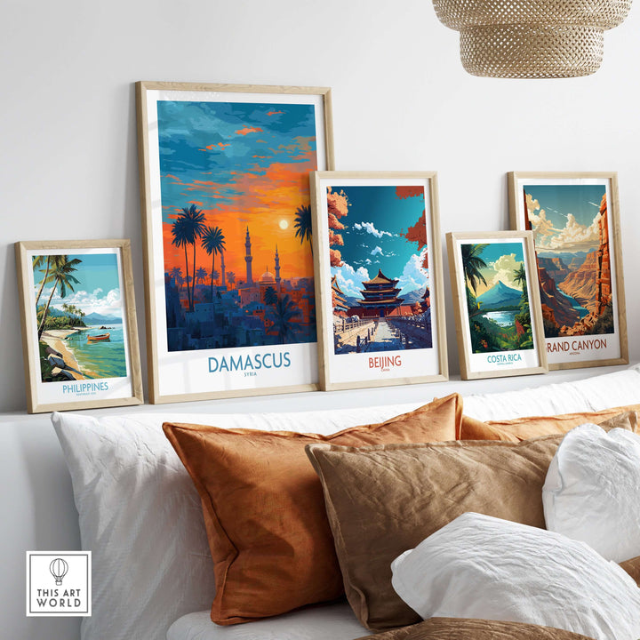 Colorful travel art prints displayed on a shelf, featuring Damascus, Beijing, Costa Rica, and the Grand Canyon.