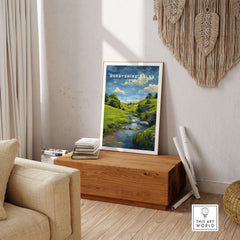 Derbyshire Countryside Print - England Green Hills Wall Art - River & Fields Travel Poster on display in a cozy living room.