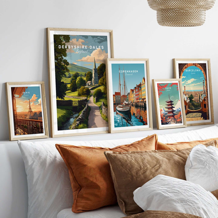 Collection of framed art prints featuring Derbyshire Dales, Copenhagen, and Barcelona wall art on a cozy bed.