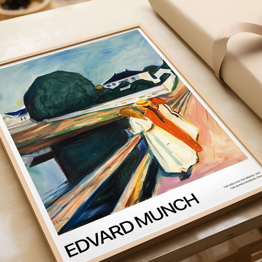 Edvard Munch Art Print - The Girls on the Bridge 1927 Painting - Museum Poster displayed in a frame on a table.