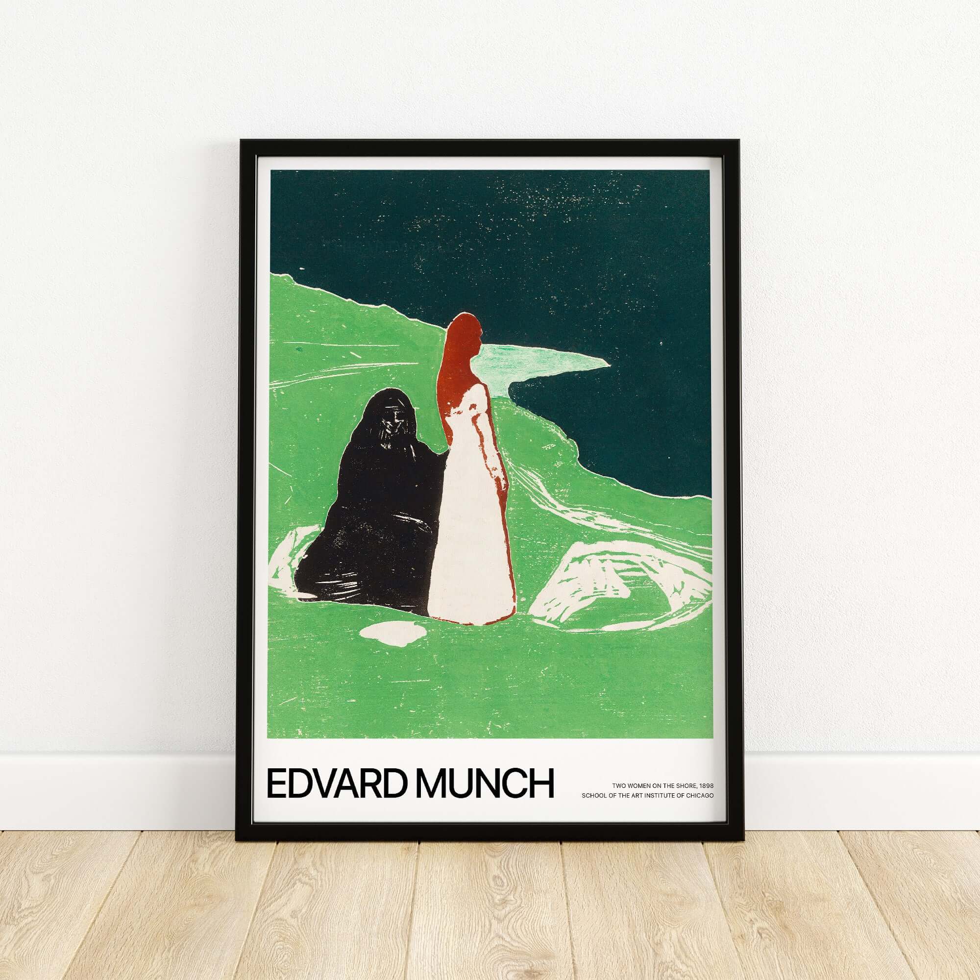 Edvard Munch Art Print - Two Women on the Shore 1898 Woodcut AIC Poster displayed in a black frame on a wooden floor.