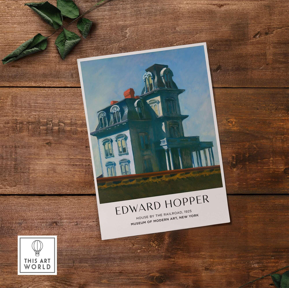 Edward Hopper House by the Railroad 1925 MoMA Art Print Poster on a wooden table.