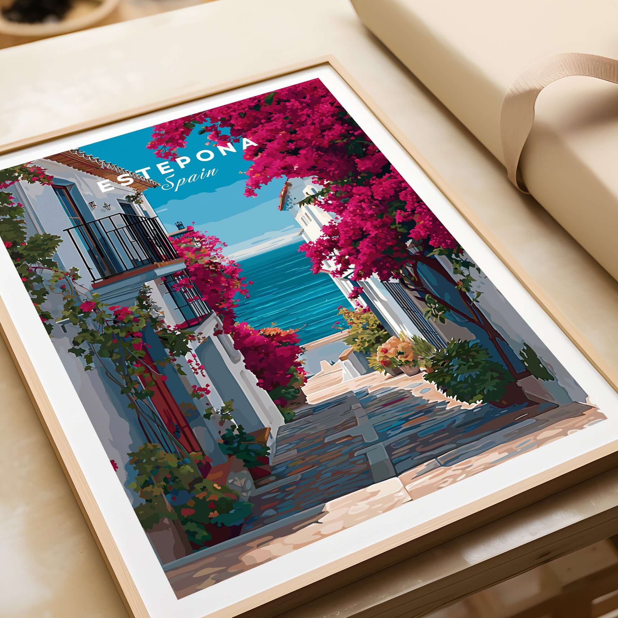 Estepona Old Town Sea View Print | Mediterranean White Village Decor displayed on a table with vibrant colors.