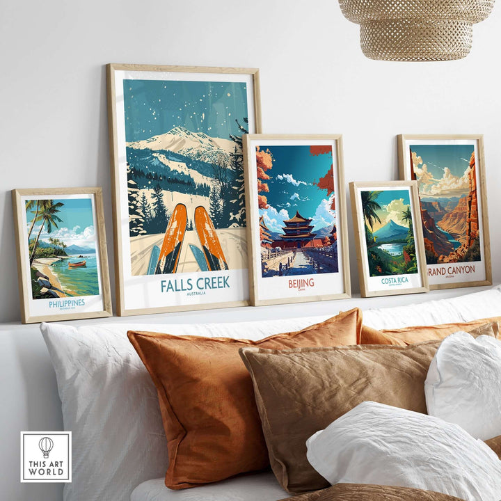 Collection of travel posters including Falls Creek ski poster, Beijing, Costa Rica, Grand Canyon, and Philippines displayed on a shelf.